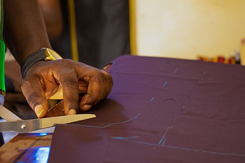 Tailor's hands cutting fabric — the craft at Lam Son Tailor